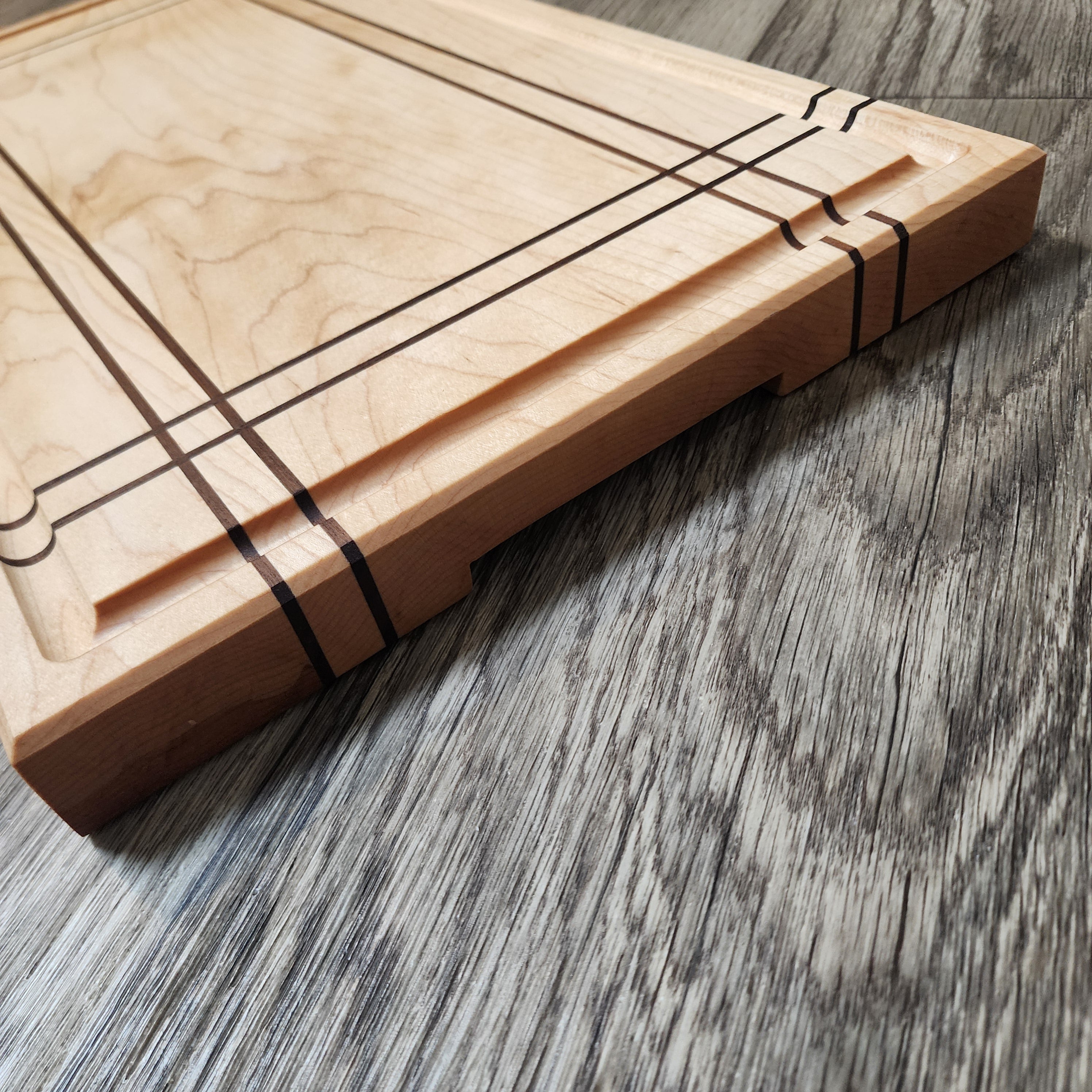 Maple Cutting Board with Walnut stripes. Features bottom finger grips and juice groove.