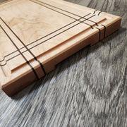 Maple Cutting Board with Walnut stripes. Features bottom finger grips and juice groove.