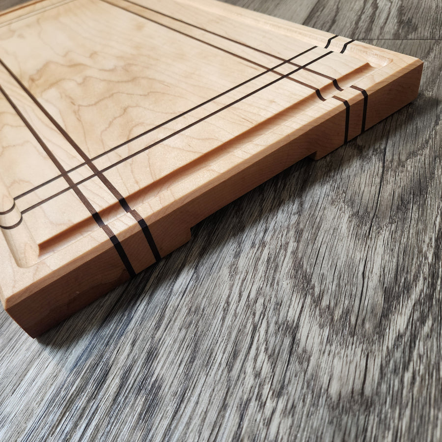 Maple Cutting Board with Walnut stripes. Features bottom finger grips and juice groove.