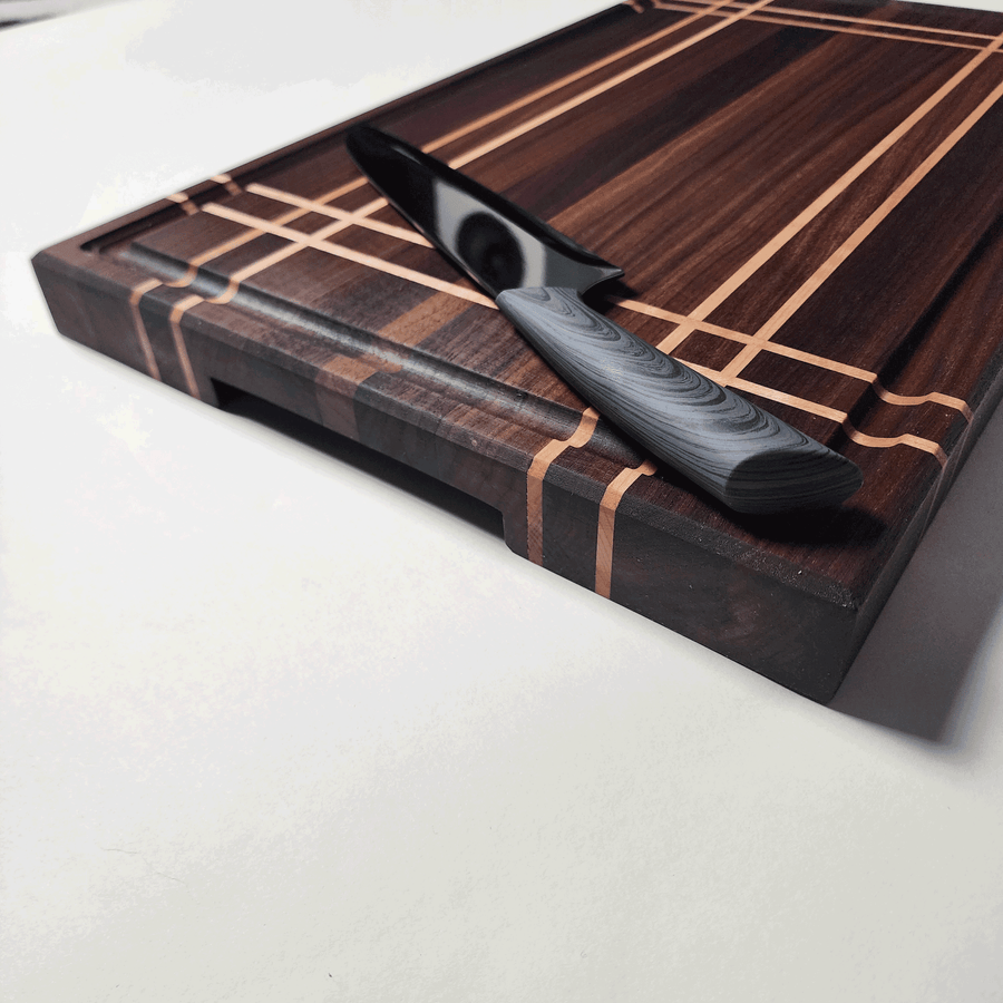 Side view of walnut and maple stripe cutting board showing bottom finger grips.