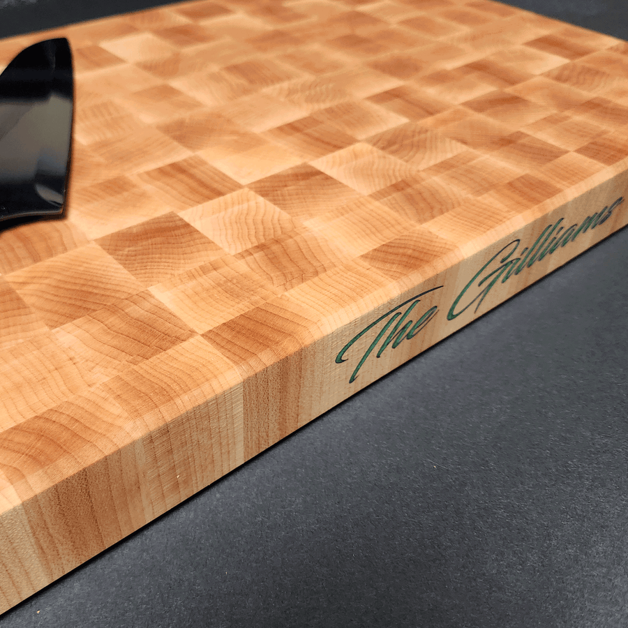 End Grain Maple Cutting Board with color filled personalized engraving on the side of the cutting board. Knife on top of cutting board for perspective.