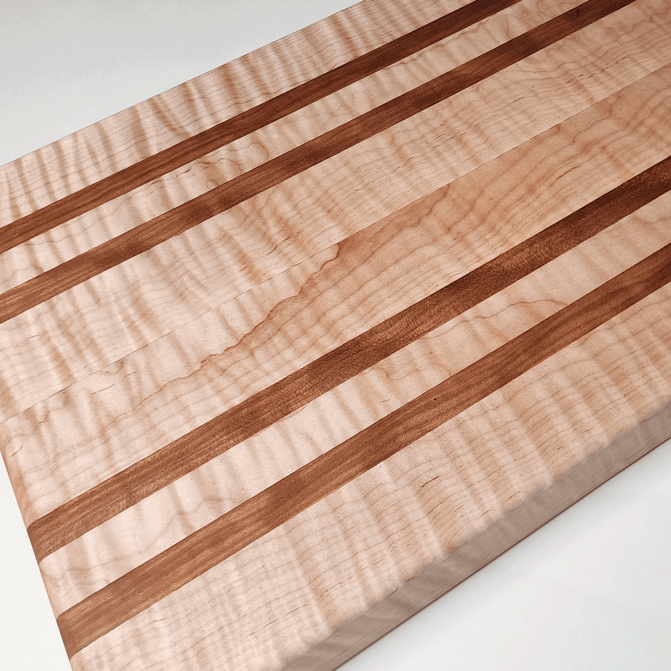 Unique maple cutting board with natural wavy pattern. Has four cherry strips in board