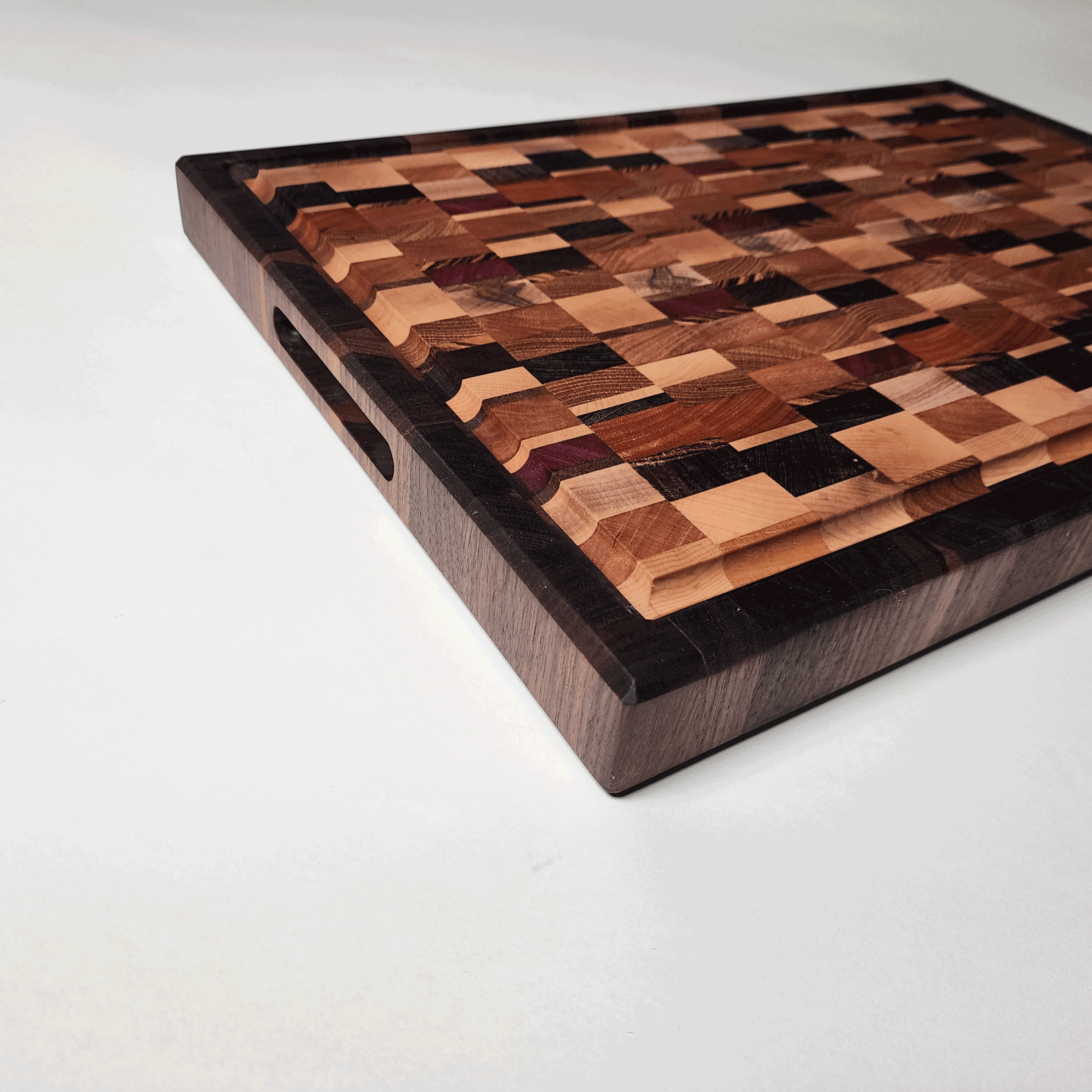angles view of chaotic end grain board with walnut border and side finger grips. 1.5" thick