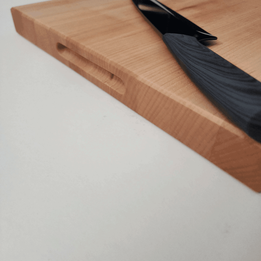 Side view of 1.5 inch thick maple cutting board. Knife on top to display size of cutting board.