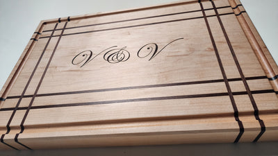 Angled view of Plaid cutting boar made from Maple hardwood and Walnut strips. Features script engraving in the center of the board